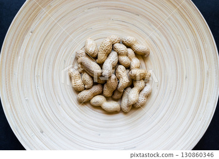 Peanuts with Nutshell Placed in Natural Bamboo Plate 130860346