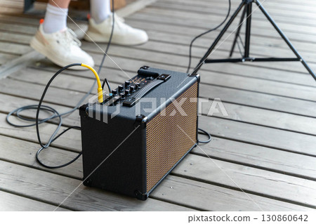 Portable guitar amplifier and microphone stand preparing for an outdoor concert 130860642