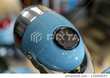 Close-up of speedometer on light blue vintage scooter headlight 130860643