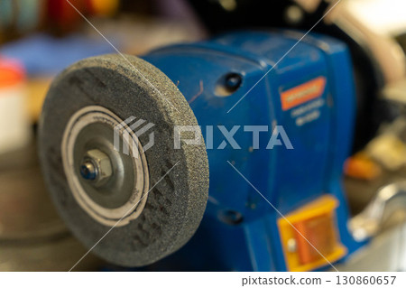 Grinding wheel spinning on bench grinder in workshop Grinding wheel spinning on bench grinder in workshop 130860657