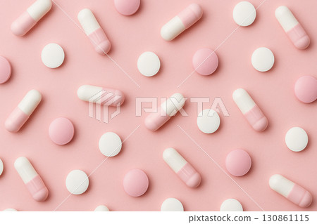 Assorted white and pink capsules and round pills scattered on pastel pink background, creating soft and modern pharmaceutical concept with clean and organized pattern 130861115