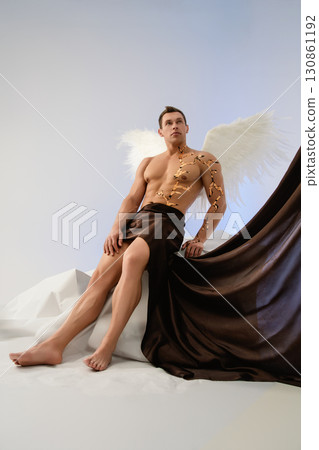 Dramatic portrayal of a man with angel wings in an artistic setting Dramatic portrayal of a man with angel wings in an artistic setting 130861192