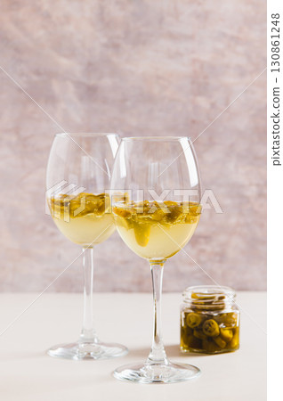 White wine infused with jalapeno slices in glasses on the table vertical view White wine infused with jalapeno slices in glasses on the table vertical view 130861248