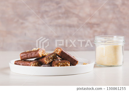 Protein bars with nuts on plate and protein powder in jar on table 130861255