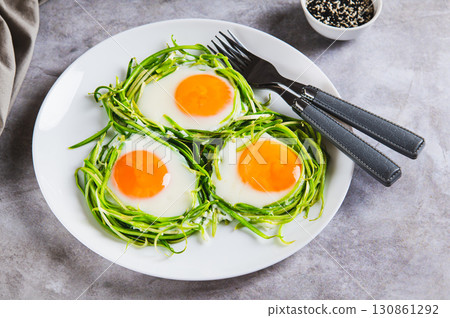 Fried eggs in zucchini noodle nests on a plate on the table Fried eggs in zucchini noodle nests on a plate on the table 130861292