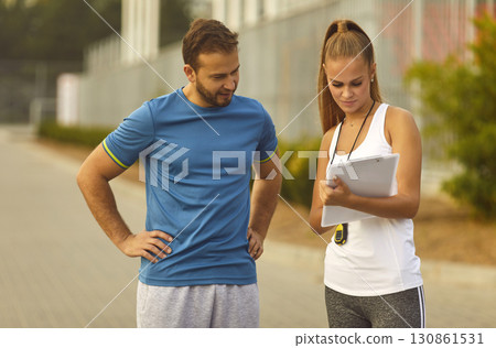 Couple watching the results of sports training outdoors checking time for performance in park. Couple watching the results of sports training outdoors checking time for performance in park. 130861531