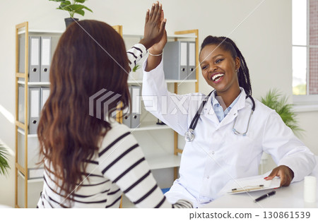 Friendly African American woman doctor gives high five to her happy healthy patient Friendly African American woman doctor gives high five to her happy healthy patient 130861539