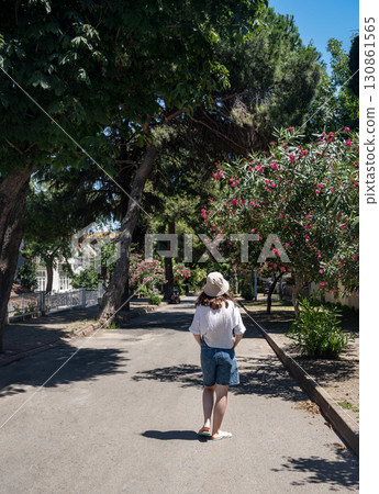 A woman tourist looks at ancient houses on the island of Kinaliada with beautiful blooming gardens 130861565