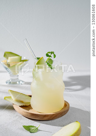 Fresh lemonade or mojito in a glass with melon, straw and mint on a wooden plate Fresh lemonade or mojito in a glass with melon, straw and mint on a wooden plate 130861608