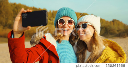 Happy young two women friends taking selfie with phone on beach, smiling girlfriends having fun 130861666
