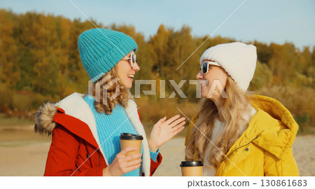 Happy two women friends talking on sunny beach, stylish girlfriends smiles together on sea coast Happy two women friends talking on sunny beach, stylish girlfriends smiles together on sea coast 130861683