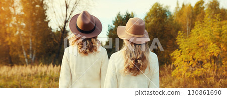 Back view two beautiful women together in autumn park, stylish girlfriends in hat, sweater outdoors 130861690