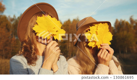 Happy two women friends with autumn yellow leaves, funny girlfriends having fun together in park Happy two women friends with autumn yellow leaves, funny girlfriends having fun together in park 130861695