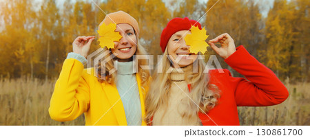 Happy young two women friends with autumn yellow leaves, stylish girlfriends smiles together in park Happy young two women friends with autumn yellow leaves, stylish girlfriends smiles together in park 130861700