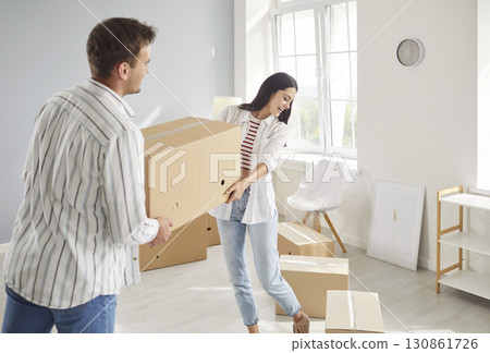 Young happy couple carrying cardboard box in new apartment on their moving day 130861726
