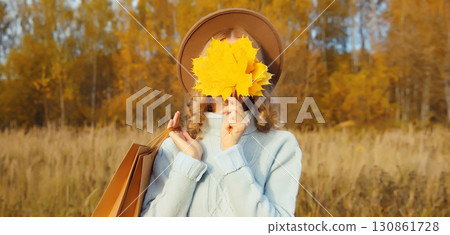 Stylish happy young woman with shopping bag, yellow leaves, girl smiling outdoors in autumn park 130861728
