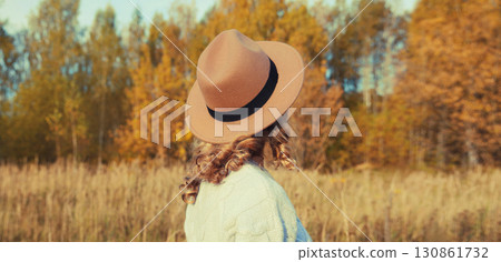 Beautiful woman in hat enjoying warm weather in autumn park with yellow leaves, nature background Beautiful woman in hat enjoying warm weather in autumn park with yellow leaves, nature background 130861732