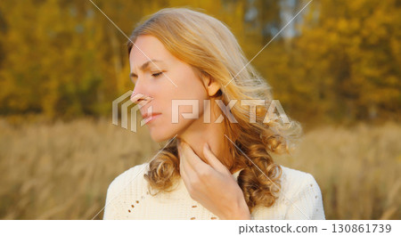 Sick exhausted woman suffering from acute sore in throat flu, touches neck with hand outdoor in park 130861739