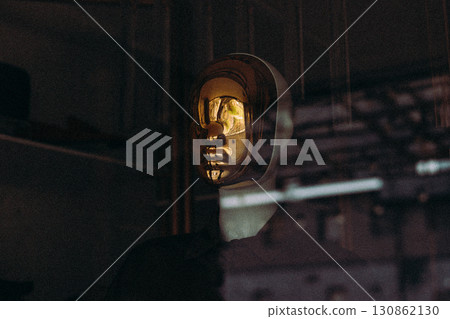 A golden mask is set against a dark backdrop, reflecting light and creating a captivating artistic display. The sleek design adds a touch of elegance. A golden mask is set against a dark backdrop, reflecting light and creating a captivating artistic display. The sleek design adds a touch of elegance. 130862130
