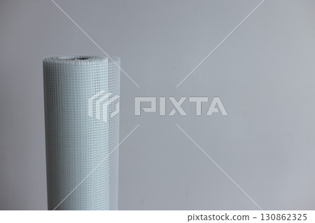 A roll of white plaster mesh for preparatory and painting works on a grey background . A roll of white plaster mesh for preparatory and painting works on a grey background . 130862325