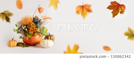 Creative autumn floral arrangement of seasonal flowers in pumpkin as vase on gray background for Thanksgiving Day. Annual decorations. Copy space. Banner. 130862342
