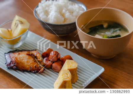 日式早餐包括烤魚、玉子燒(蛋捲)、香腸、奇異果、米飯和味噌湯 日式早餐包括烤魚、玉子燒(蛋捲)、香腸、奇異果、米飯和味噌湯 130862993