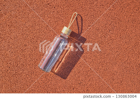 Reusable glass water bottle at stadium on sunny day 130863004