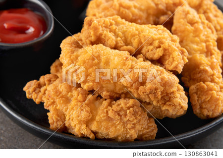 Crispy chicken breast strips with ketchup on a dark background. Close-up. Fast food. 130863041