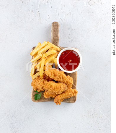 Crispy chicken strips with ketchup and French fries on a wooden board. Fast food. White background 130863042