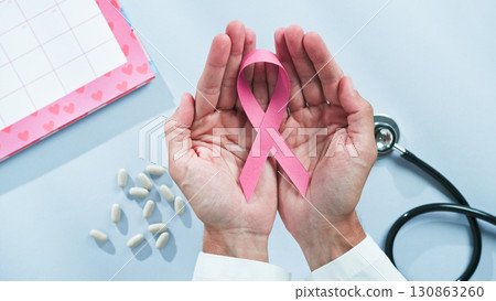 Doctor's hands hold pink bow 130863260