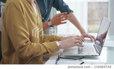 Team collaboration over financial reports. Business people, professionals analyzing financial charts and data on a desk while sitting near a laptop computer 130864748