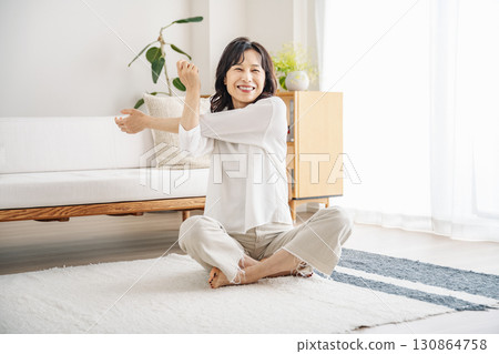 Middle-aged woman stretching in the living room at home 130864758