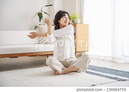 Middle-aged woman stretching in the living room at home 130864759