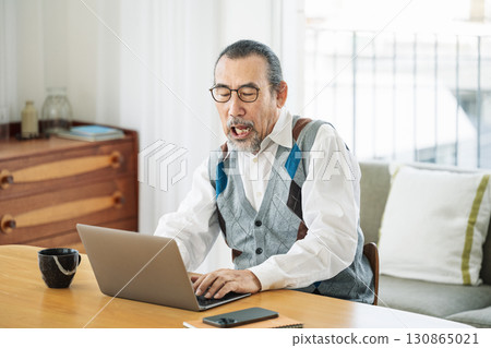 Senior man working on a computer in the living room at home Senior man working on a computer in the living room at home 130865021