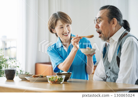 一位女性護理員正在幫助一位老人用餐 一位女性護理員正在幫助一位老人用餐 130865024