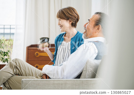 Senior couple watching TV happily on the sofa at home Senior couple watching TV happily on the sofa at home 130865027