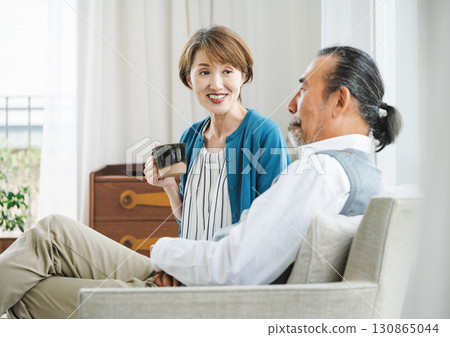 A middle-aged couple having a pleasant conversation on the sofa 130865044