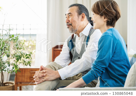 Profile of a senior couple sitting on a sofa in the living room at home 130865048