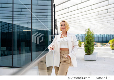 Businesswoman standing by glass railing near 130865180