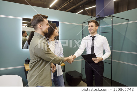 Young Couple Shakes Hands with Salesman After Successful Purchase 130865748