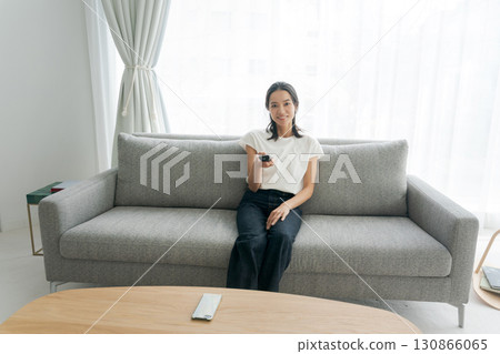 女人坐在沙發上，看電視 130866065