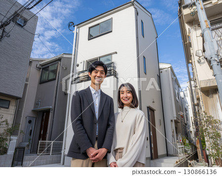 A small three-story house and a smiling salesman A small three-story house and a smiling salesman 130866136