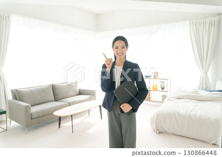 A woman in a suit showing around a model room 130866448