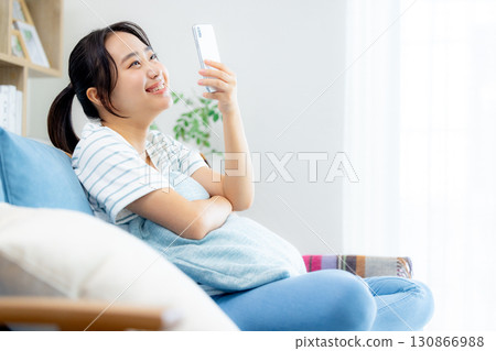 一個女人在客廳裡看著她的智能手機 130866988