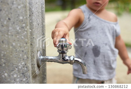 Baby's hand turning off the tap in a summer park 130868212