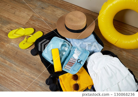 An open suitcase with clothes, cosmetics and travel accessories.  130868236