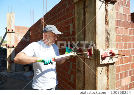 A worker installs a spring clamp for securing the formwork on the construction site. A worker installs a spring clamp for securing the formwork on the construction site. 130868294