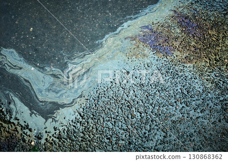 Brightly colored gasoline stain producing abstract forms on the soaked asphalt after rainfall. Brightly colored gasoline stain producing abstract forms on the soaked asphalt after rainfall. 130868362