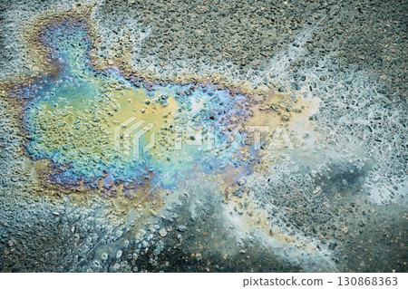 An oil slick on wet pavement refracts light, creating a vibrant array of colors and patterns, showcasing nature's art in a bustling city environment after rainfall. An oil slick on wet pavement refracts light, creating a vibrant array of colors and patterns, showcasing nature's art in a bustling city environment after rainfall. 130868363