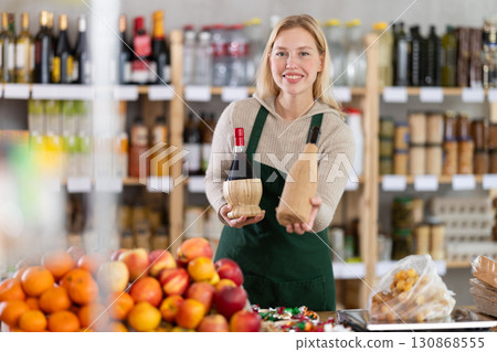 Young woman seller offering wine in grocery store 130868555